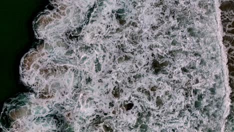 a beach with a wave coming in to the shore and a sandy beach with a green ocean and a sandy shore