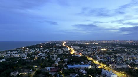 wide angle drone shot of urban cityscape with lit5 up street lights on roads during dusk.