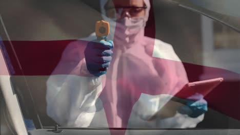 English-flag-waving-scientist-wearing-protective-clothes-with-digital-tablet-holding-temperature-gun