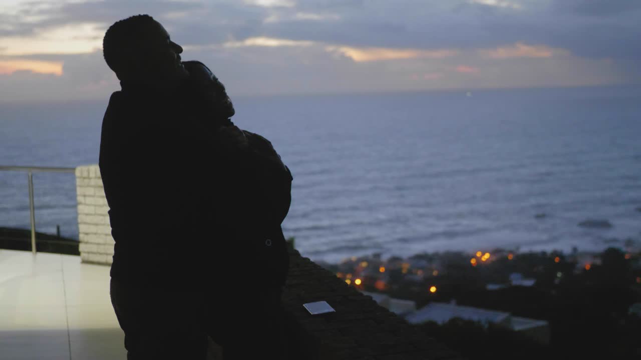 Couple Sharing a Romantic Moment Overseeing The Ocean at Sunset on a Balcony in Camps Bay, Cape Town