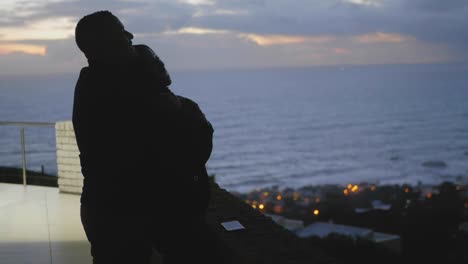 couple sharing a romantic moment overseeing the ocean at sunset on a balcony in camps bay, cape town