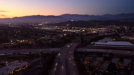 Carretera-Con-Drones-En-Estados-Unidos-Al-Atardecer-Con-Montañas-Al-Fondo