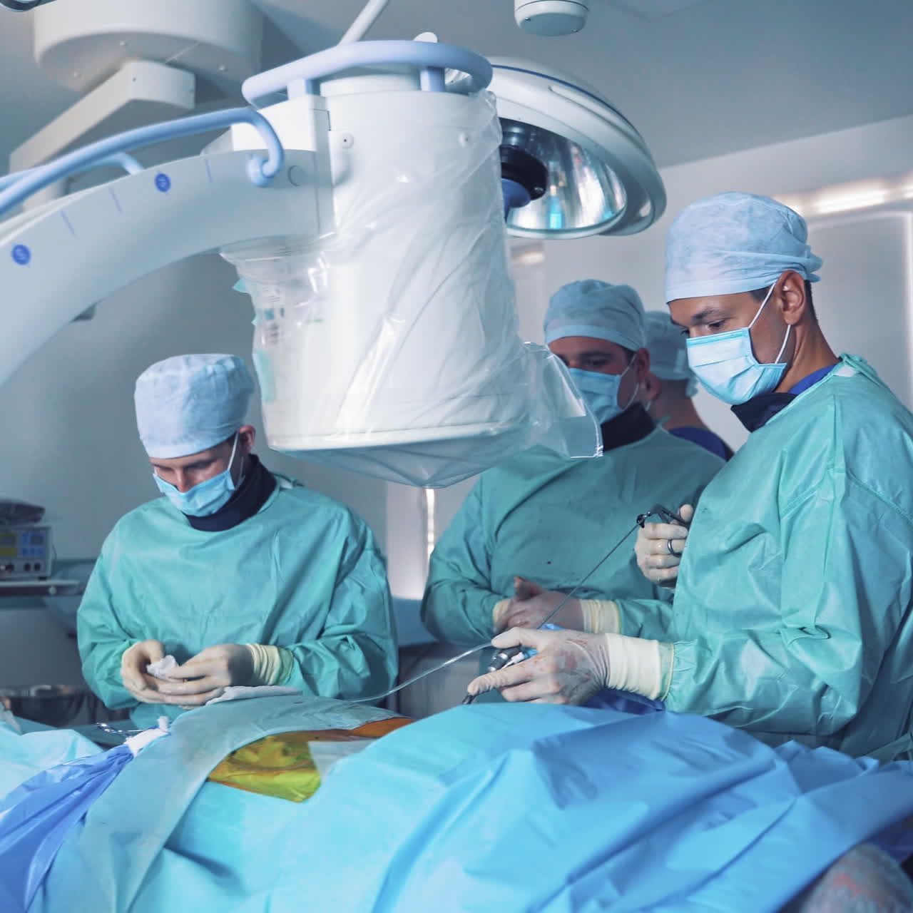 Doctors look at monitor while doing an operation. Team of surgeons in medical uniform performing operation with the help of new modern equipment in surgery room.