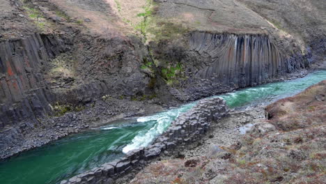 wide establishing shot of a basalt canyon with a green water river