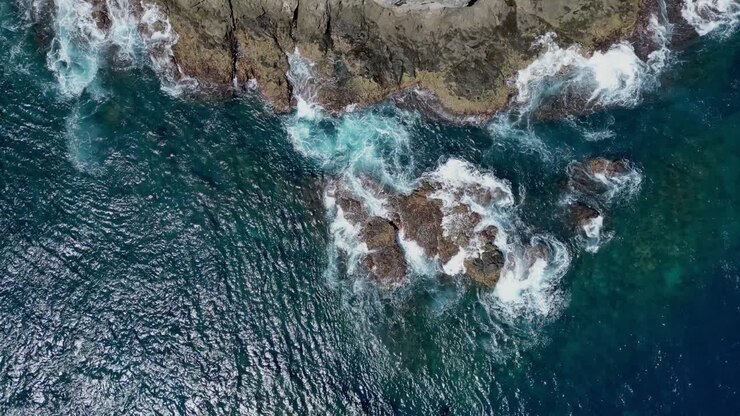 visão aérea de drones de ondas quebrando em uma costa rochosa