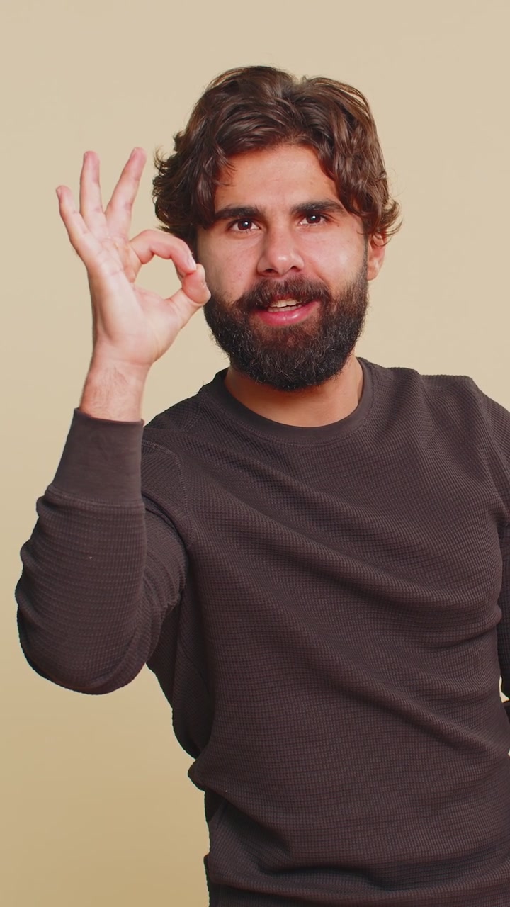 Uomo libanese gioioso e felice, con maniche lunghe, che guarda la telecamera con approvazione su sfondo beige.