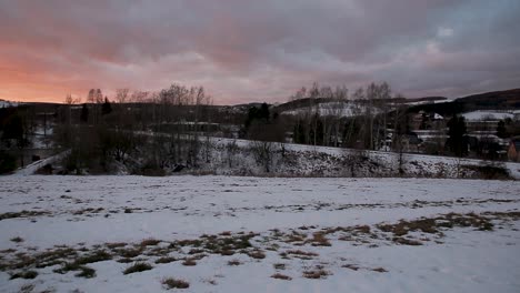 campo cubierto de nieve al atardecer con un fondo rural sereno y un toque de colores cálidos del cielo