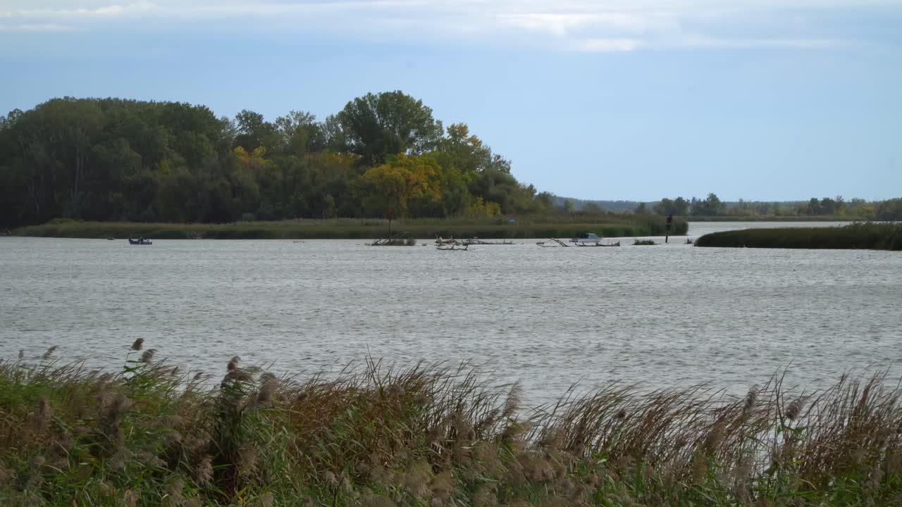 Local small fishing and recreational boats navigate through the canals of Lake Tisza at Abadszalok Basin from a distance on an autumn day in Hungary.