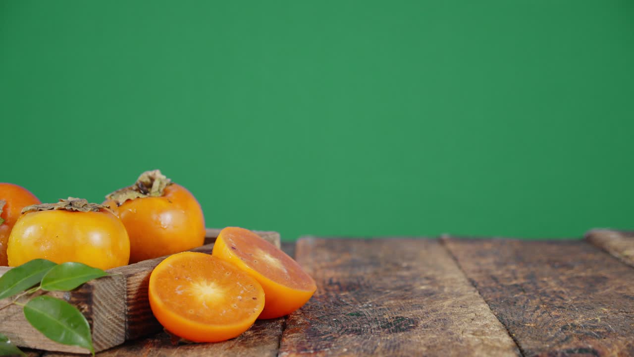 y mitades enteras de un caqui maduro en una mesa de madera.