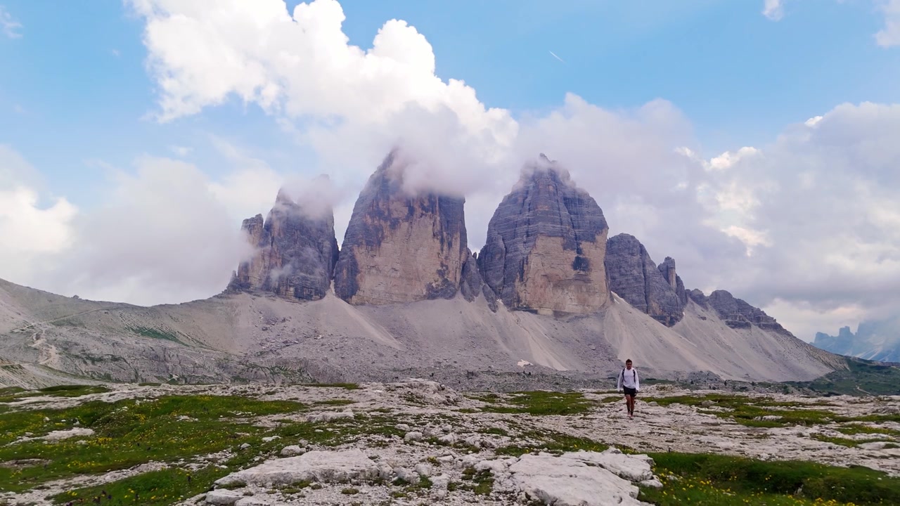 Il drone si allontana, riprendendo un viaggiatore solitario che si allontana dalle Dolomiti sullo sfondo.