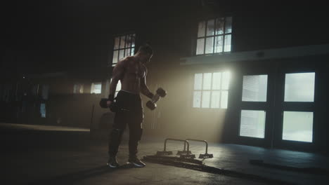man doing dumbbell bicep curls in a gym