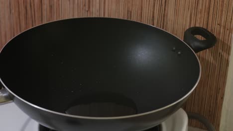 pouring cooking oil from ramekin into wok – static shot