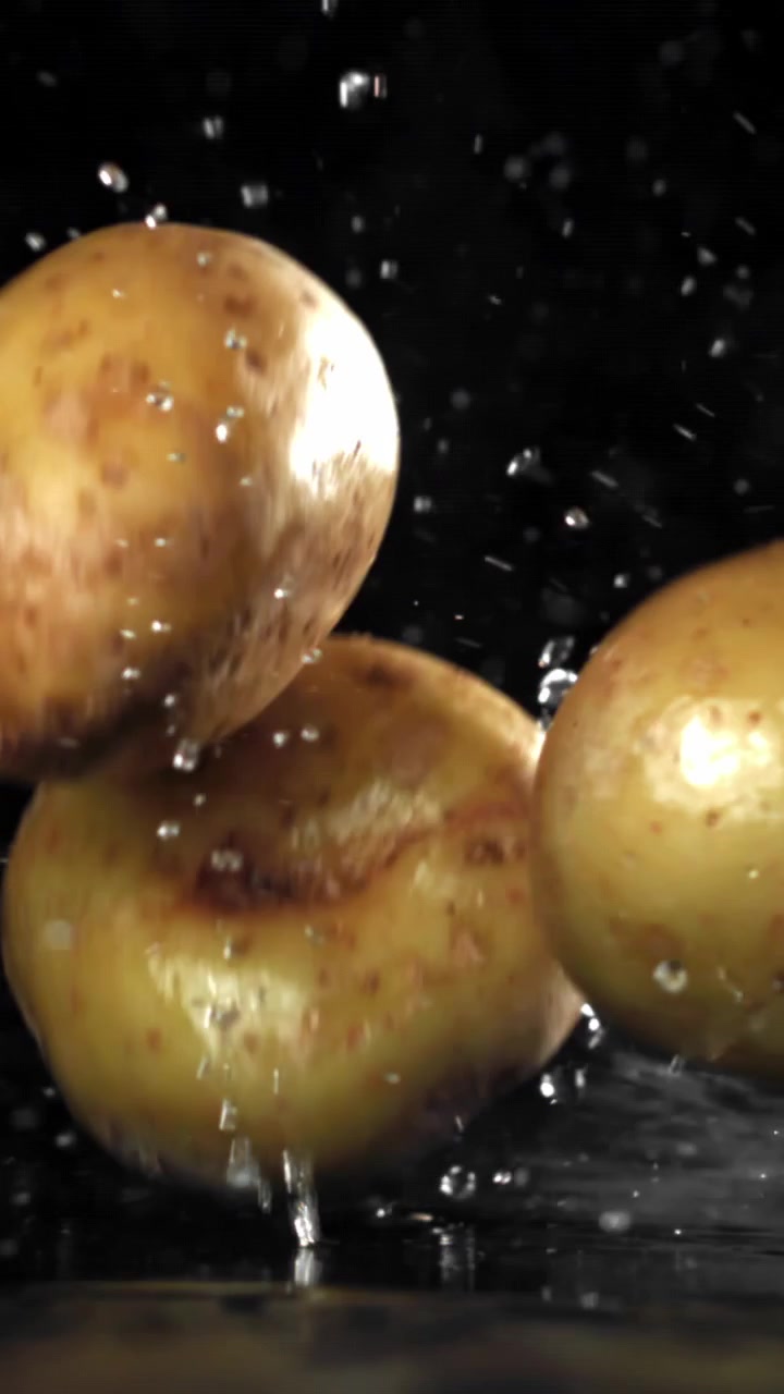 Patate fresche che cadono e schizzano acqua al rallentatore