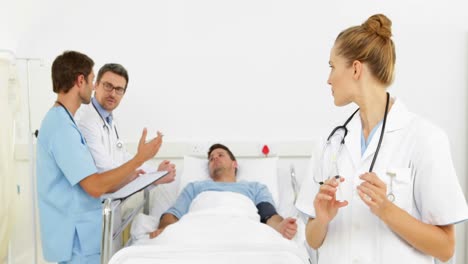 Médicos-Hablando-Con-Un-Paciente-Enfermo-En-La-Cama-Mientras-La-Enfermera-Prepara-La-Inyección