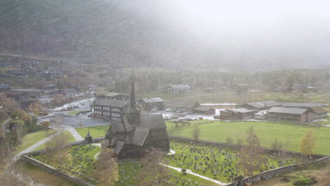 stave church surrounded with tombstone during snowstorm in lom, norway