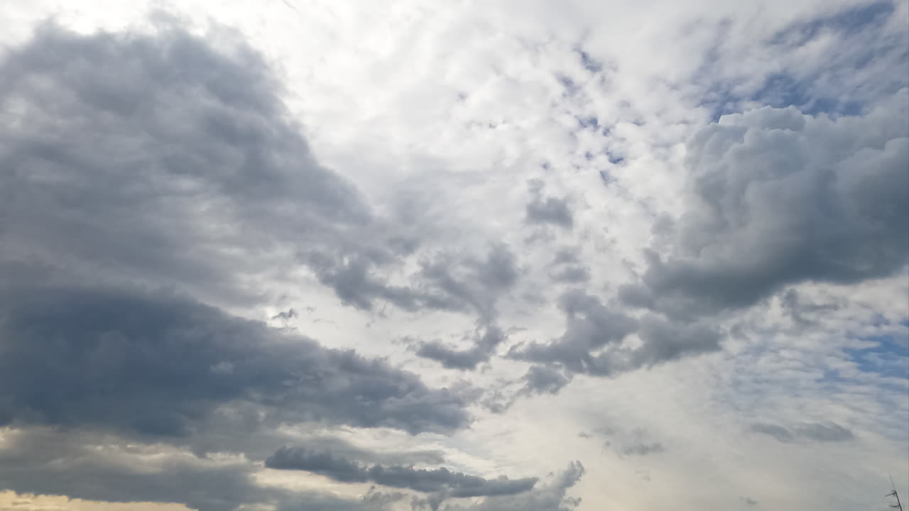 Diverse types of clouds formation in the sky. Grey cloudscape accumulating in atmosphere. Low angle timelapse.