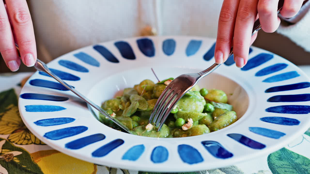 Woman eating gnocchi with pesto at an Italian restaurant