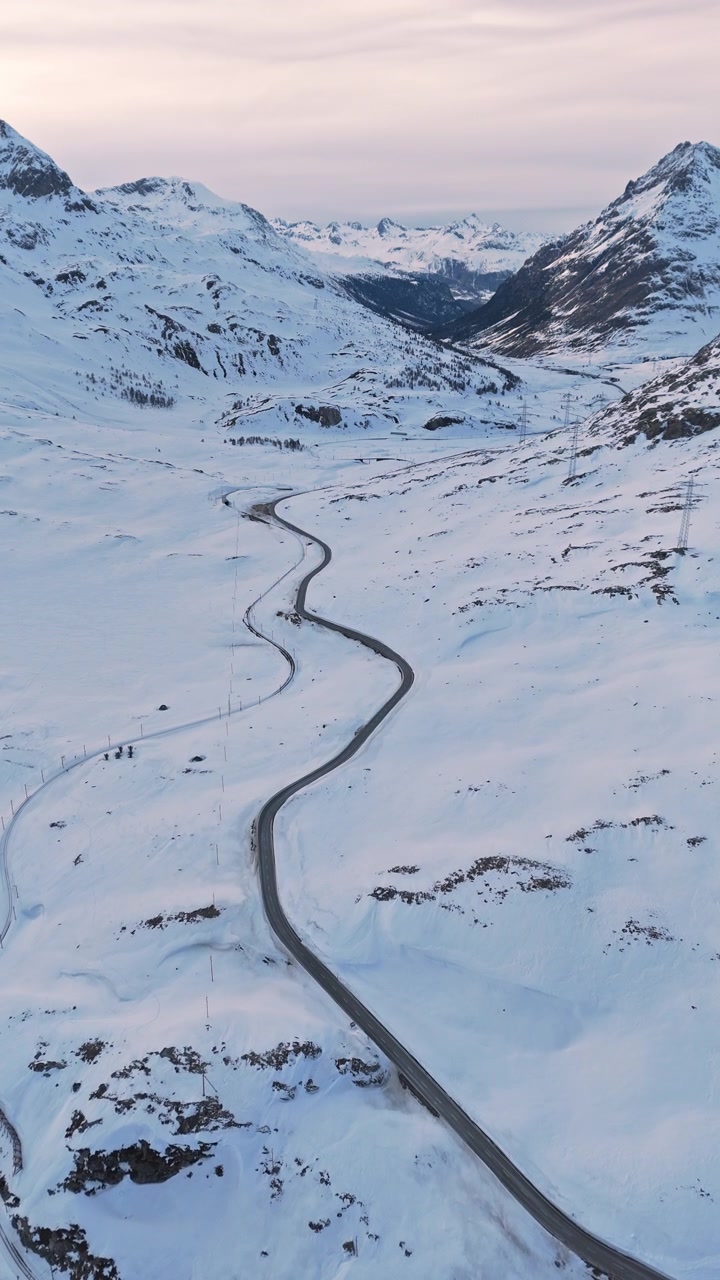Winding snowy road through Bernina Pass, serene winter landscape shot