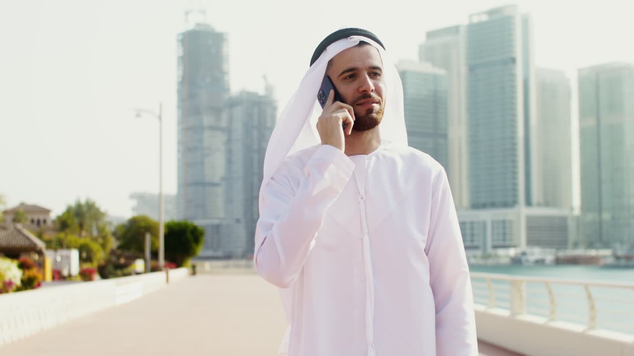 hombre con ropa tradicional hablando por teléfono en la ciudad de dubai