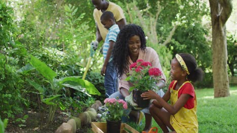 animation of happy african american family planting flowers together in garden