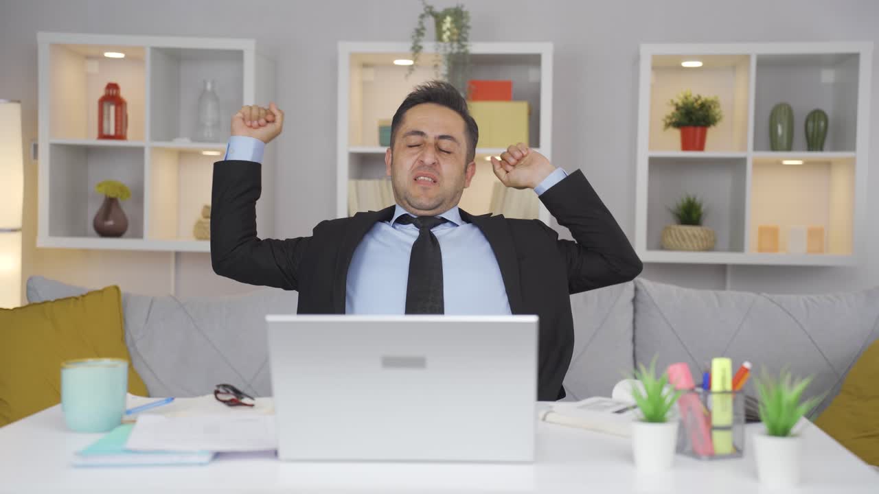 Home office worker man yawns and relaxes at the camera.