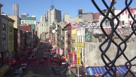 establishing shot of the chinatown district of new york city through a chain link fence