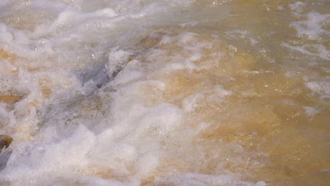 slow motion, clear water wave splashing into a small rock at the beac