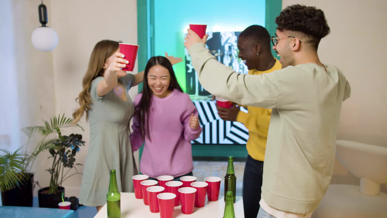 Multiethnic young friends playing beer pong at home