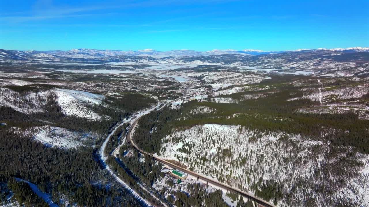 Colorado Rocky Mountain National Park Fraser downtown Winter Park ski resort mountain town aerial drone Grandby Grand Lake winter December snow blue sky sunny blanket of snow forward pan up motion