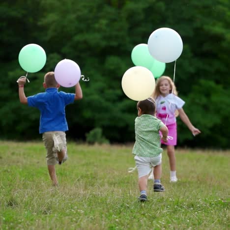 children are running with colorful balloons in the park. boys and girls having fun together outdoor