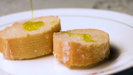 verter aceite sobre dos rebanadas de pan en un plato blanco