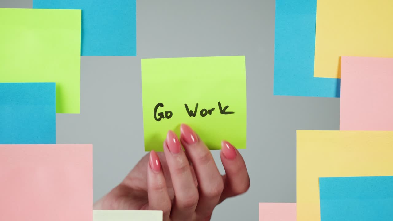 Hand Picking Up 'Go Work' Sticky Note from Wall