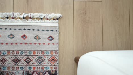 piso de madera beige con una alfombra y un sofá de colores