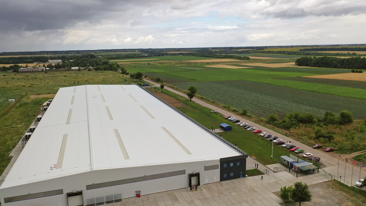 White commercial building among nature. Modern industrial plant with cars nearby in a summertime. Exterior of innovative center. Aerial view.
