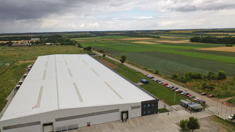 white commercial building among nature. modern industrial plant with cars nearby in a summertime. exterior of innovative center. aerial view.