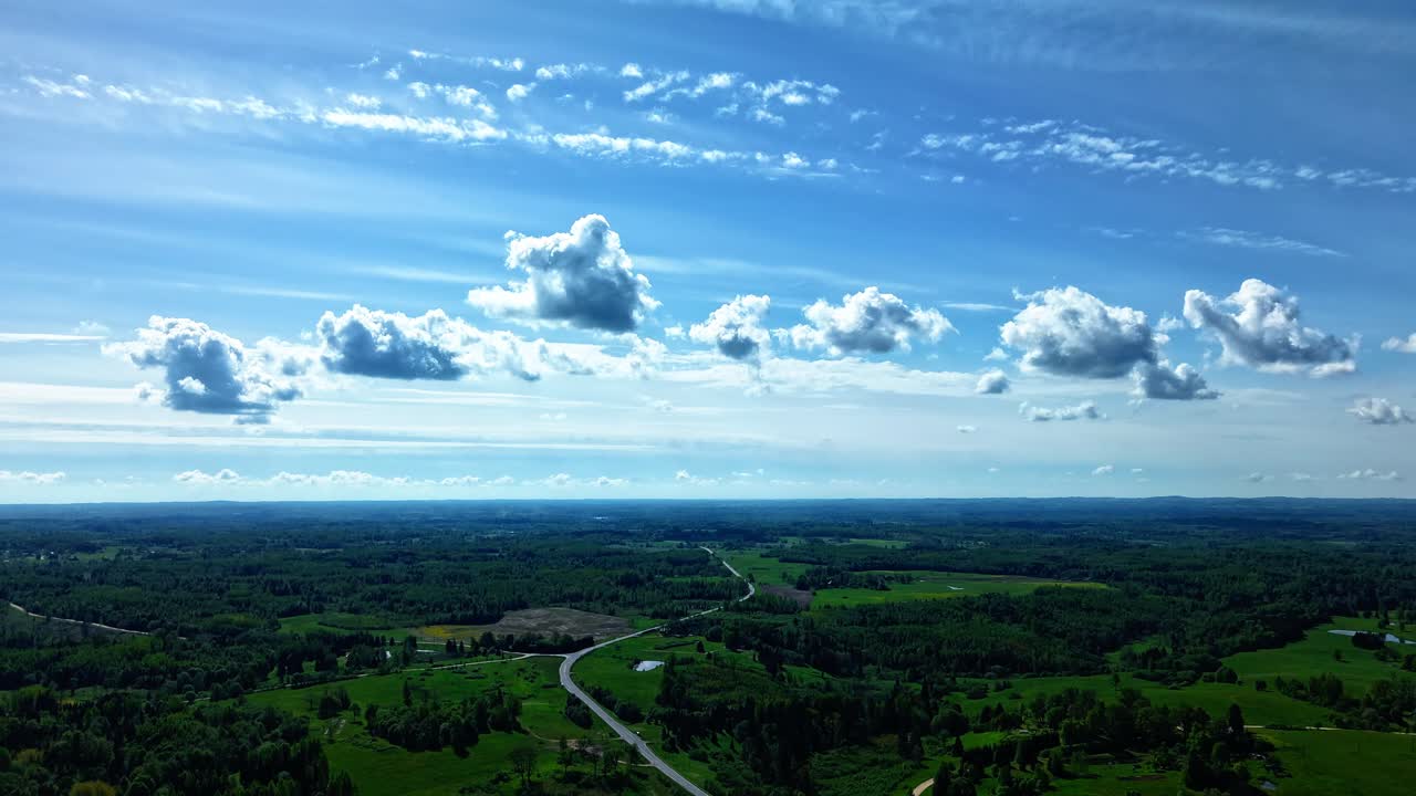 Fast drone hyperlapse showing blue skies and scattered clouds over rural countryside, clouds billowing