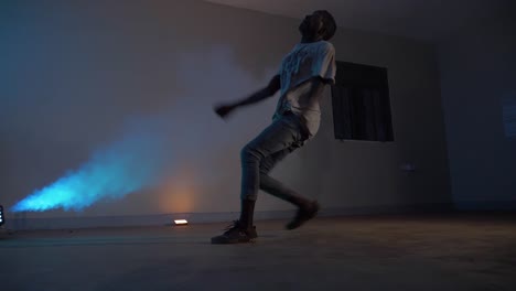 slow motion shot of african youth doing a running back flip in disco lights and with blue smoke blowing