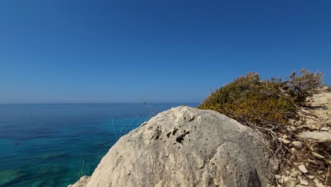 Cinematic-panoramic-seaside-with-rocks-and-blue-turquoise-sea-water-in-Mediterranean,-quiet-ideal-beach-for-summer-vacation