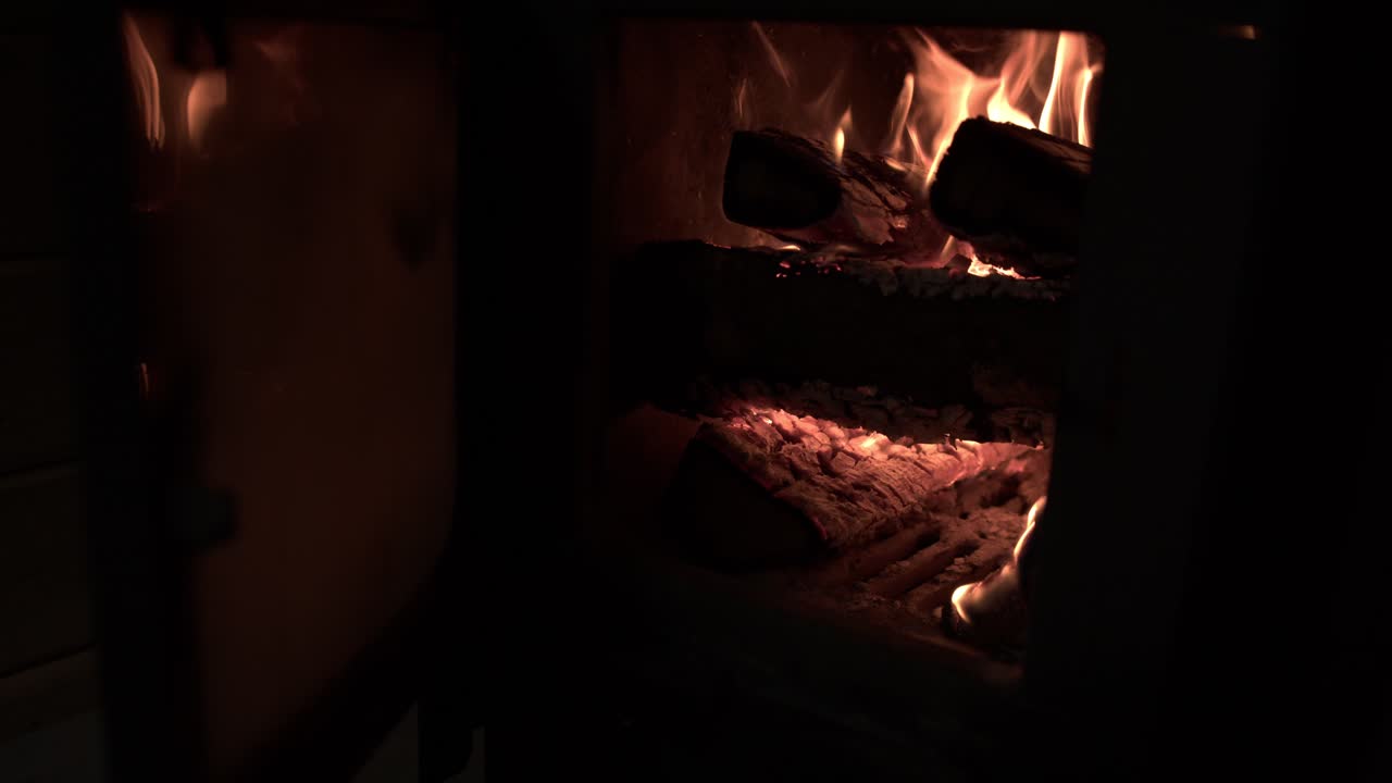 사우나 오븐에서 불타는 나무의 정적  ⁇ , 유리 문이 열려 불꽃을 드러 ⁇ 니다.