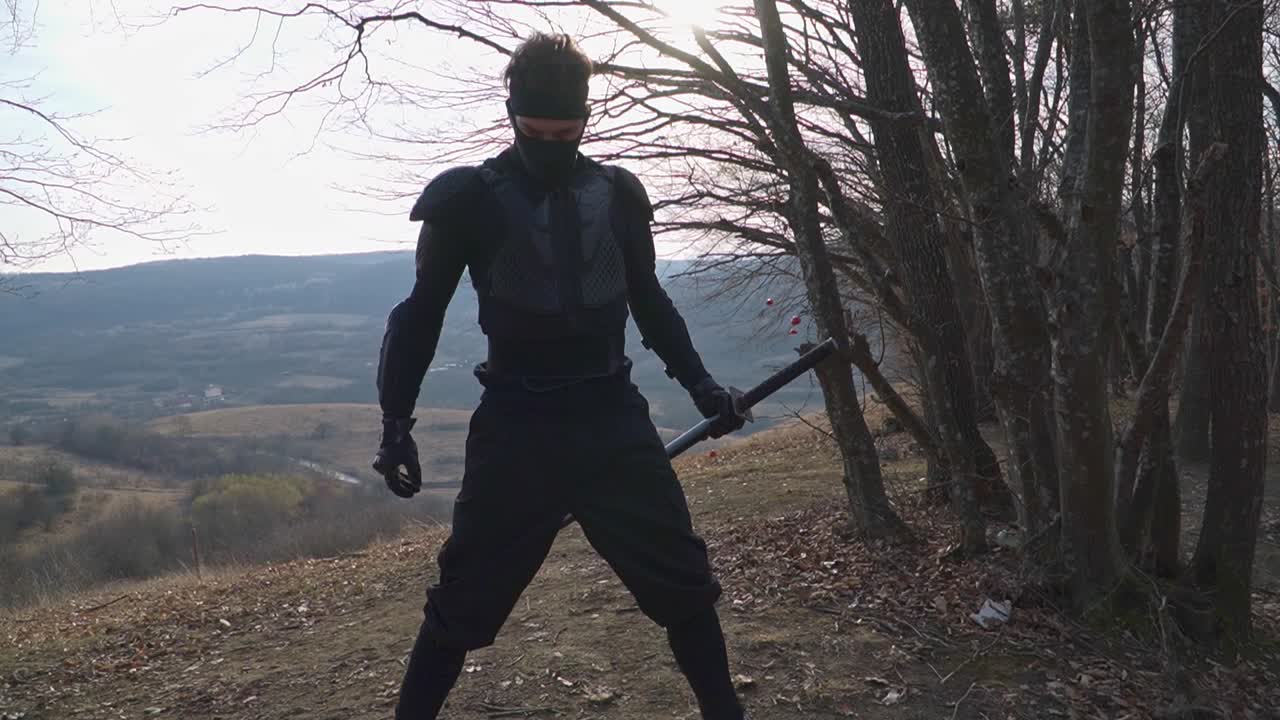 A fierce ninja warrior in black armor grips a katana, standing ready for battle on a scenic mountain. Ideal for action, martial arts, samurai, and cinematic projects
