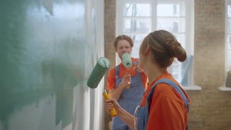 cheerful family singing with paint rollers during home repair in new apartment.