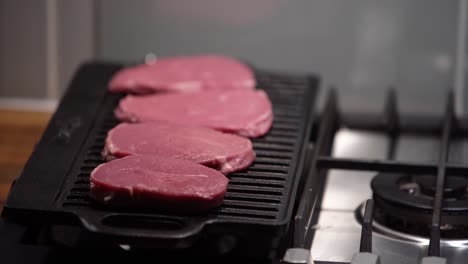 adding raw steaks to an iron griddle