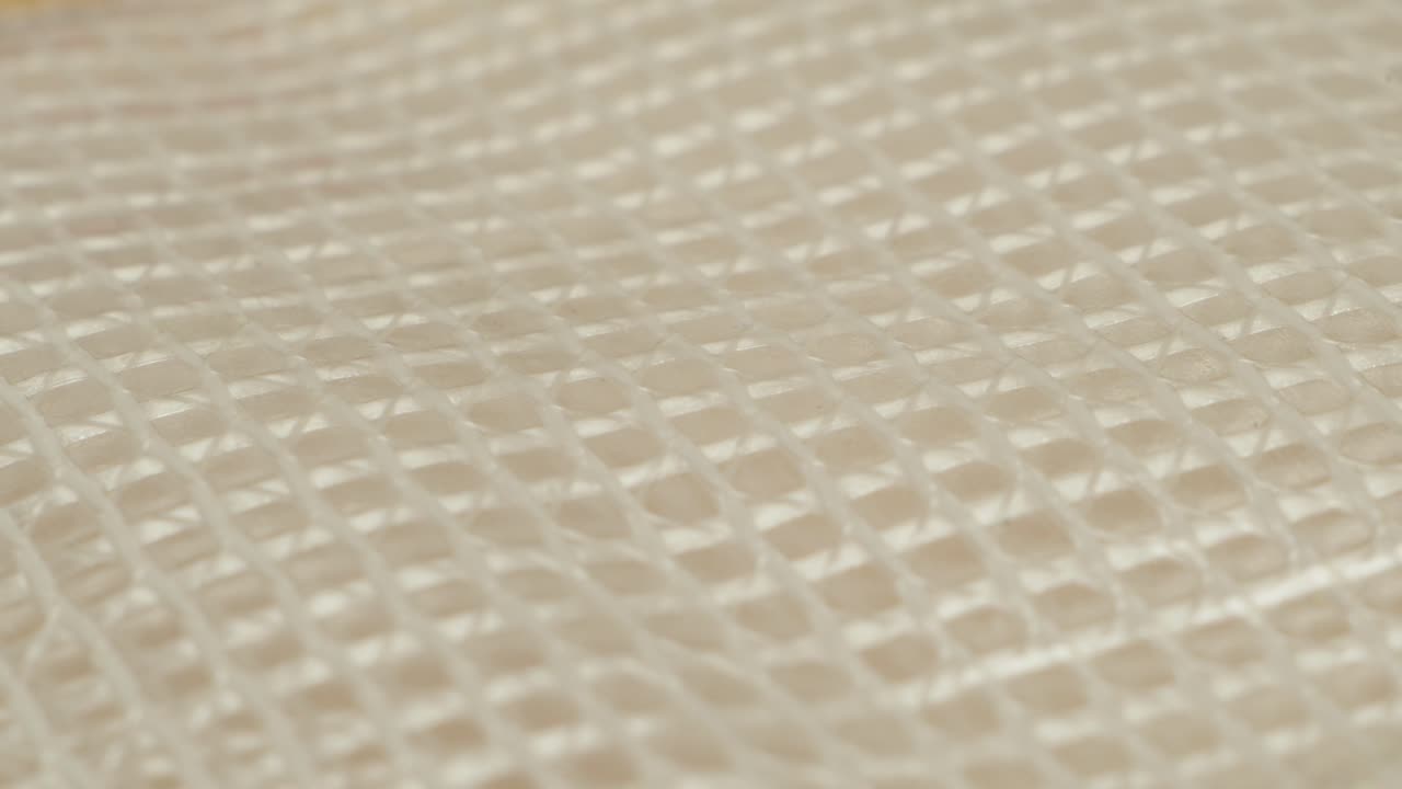 Macro footage of a white woven fabric structure, showing texture and subtle shadow play. Ideal for textile design and surface studies