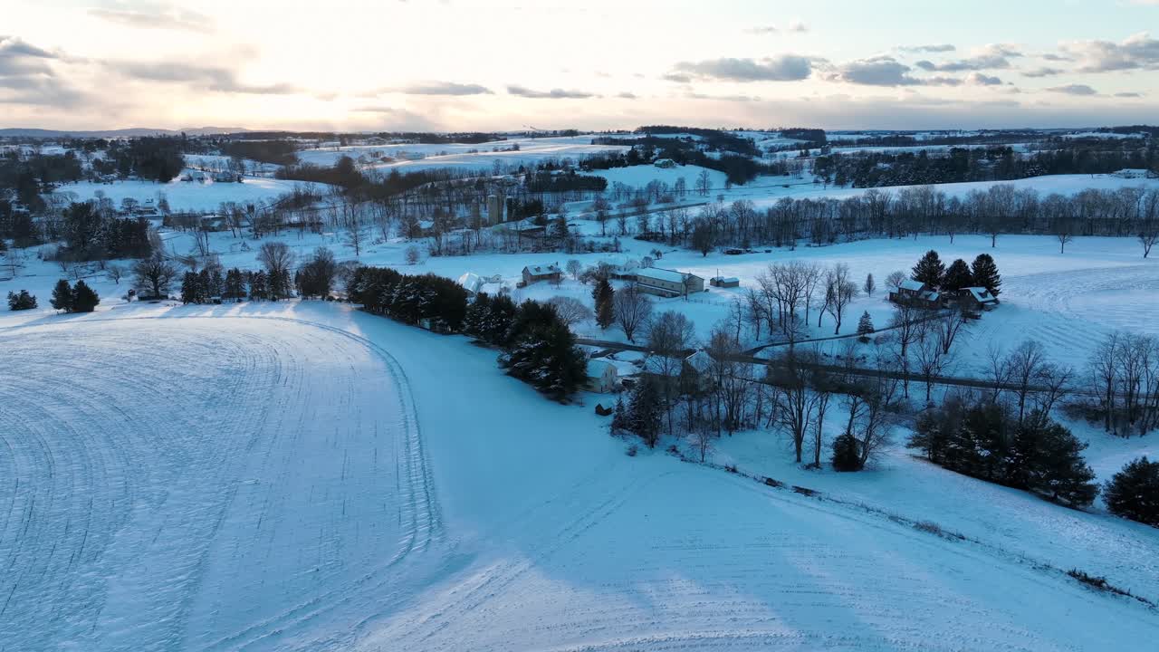 Luftfoto av snødekte vinteråkerlandskap ved solnedgang i Amerika. Bredt bilde. Bil på veikryss. Skumringsscene. Åser og landsbygd i et landlig område