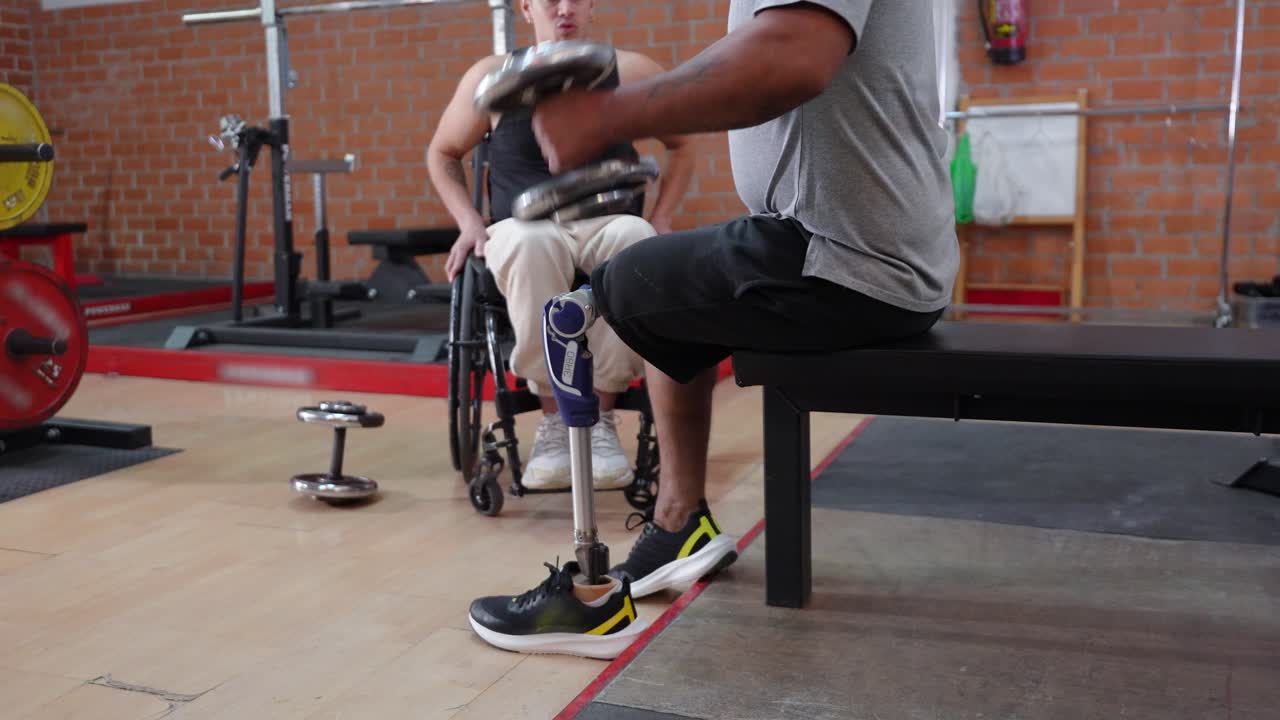 Man with Prosthetic Leg Exercising with Dumbbells in Gym with Friend