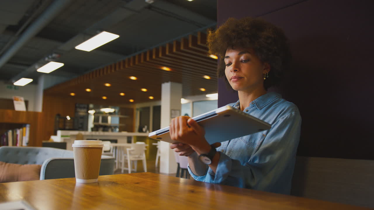 primer plano de una mujer de negocios en una oficina moderna trabajando en una computadora portátil en una cápsula de asiento con bebida para llevar