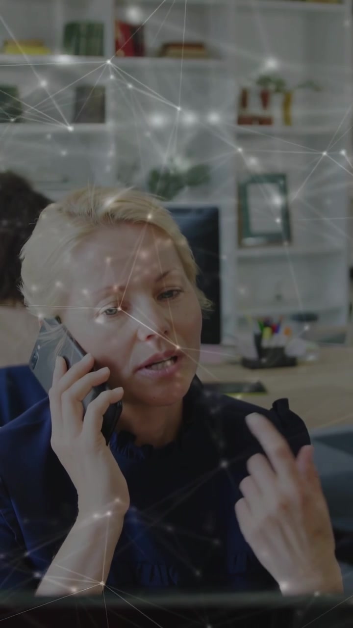 Woman taking incoming call and speaking at monitor for business update, network overlaying scene
