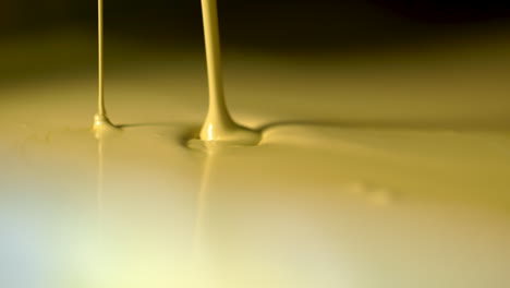 camera pan up to an extreme closeup of pale yellow paint endlessly pouring out of a valve