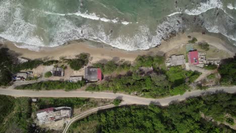 zenith drone shot over plants, houses, asphalt road and sea waves on la guaira’s caribbean coast.