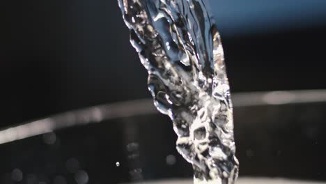 stream of beautiful clear water being poured out of glass bottle, light reflections, elegant, important hydrate, selfcare, highspeed, slowmotion